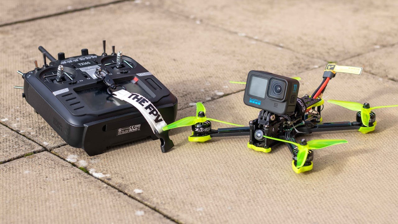 Services Close-up of FPV drone with action camera and controller on outdoor pavement, ready for flight.